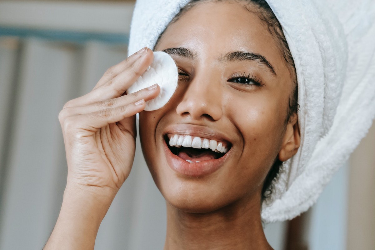 Smiling woman wiping her face with a cotton pad